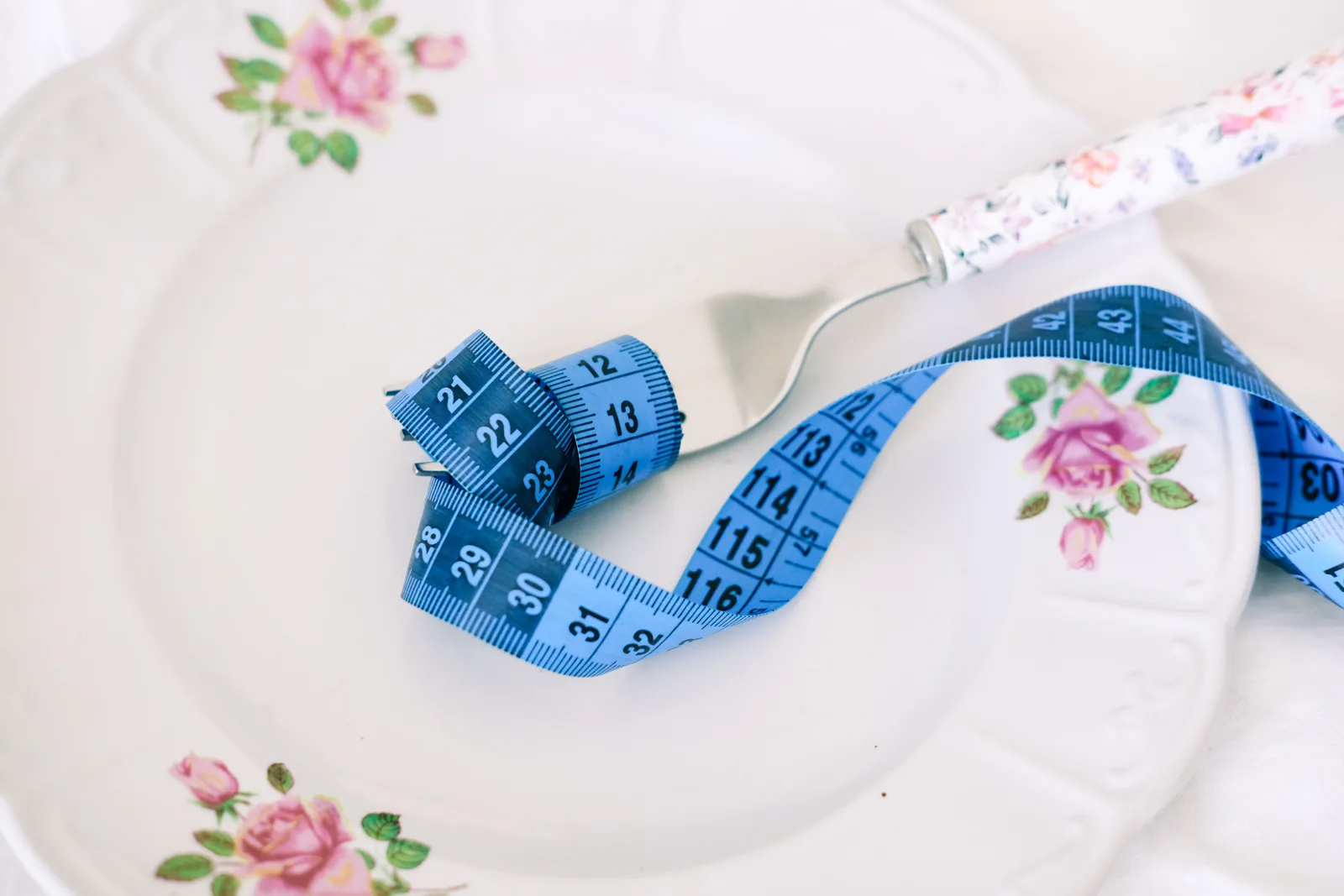 An empty plate with a fork and a tape measure